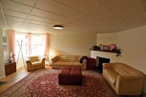 Living area with a fireplace, wood finished floors, a paneled ceiling, and crown molding