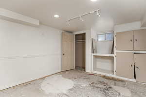 Unfurnished bedroom featuring rail lighting and a closet