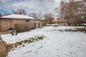 Yard covered in snow featuring a storage shed