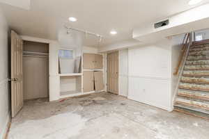 Finished basement with stairway, track lighting, and recessed lighting
