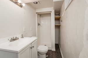 Full bathroom featuring a stall shower, vanity, and dark wood-type flooring