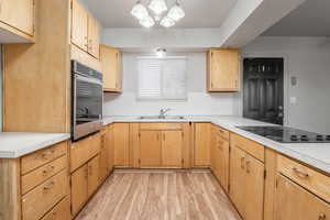 Kitchen with light countertops, pendant lighting, oven, light wood-type flooring, and black electric cooktop