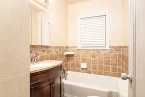 Full bath with a textured wall, vanity, and a garden tub