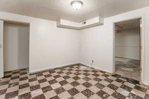 Unfurnished bedroom featuring a textured ceiling and tile patterned floors