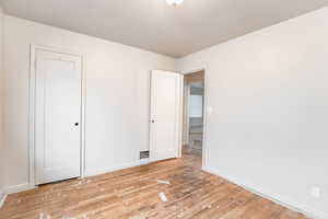 Unfurnished bedroom with wood-type flooring and baseboards