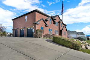 View of side of property featuring a garage, brick siding, and driveway