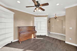 Sitting room featuring carpet floors, crown molding, arched walkways, a ceiling fan, and a chandelier