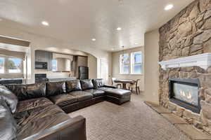 Living room featuring arched walkways, recessed lighting, a fireplace, a textured ceiling, and plenty of natural light