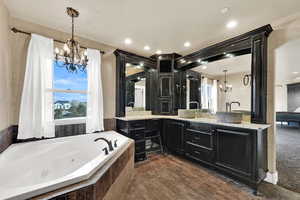 Bathroom with a chandelier, vanity, a jetted tub, plenty of natural light, and recessed lighting