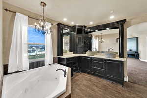 Full bathroom with a chandelier, vanity, a tub with jets, and recessed lighting