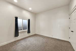 Spare room featuring baseboards and dark colored carpet