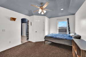 Carpeted bedroom featuring arched walkways, vaulted ceiling, and ceiling fan