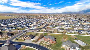 Aerial view of property and surrounding area featuring nearby suburban area and a mountainous background
