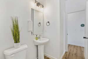 Half bathroom featuring toilet and wood finished floors