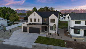 Modern farmhouse with a mountain view, a standing seam roof, a metal roof, and driveway
