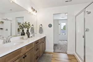 Bathroom featuring a stall shower, double vanity, and light wood-style flooring