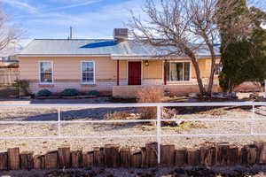 Ranch-style home with a metal roof, brick siding, covered porch, and a chimney
