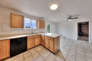 Kitchen featuring a peninsula, light countertops, dishwasher, a wood stove, and light tile patterned flooring