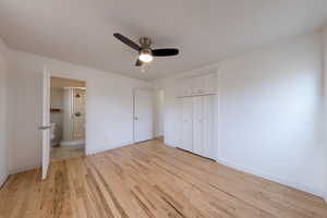 Primary bedroom featuring light wood finished floors, a ceiling fan, ensuite bath, and a closet