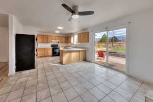 Kitchen featuring freestanding refrigerator, a peninsula, light countertops, black range with electric stovetop, and ceiling fan