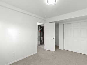 Unfurnished bedroom with carpet flooring, a closet, and water heater