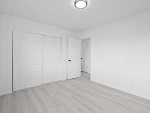 Unfurnished bedroom featuring light wood-style flooring and a closet