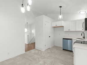 Kitchen featuring dishwashing machine, white cabinetry, lofted ceiling, decorative light fixtures, and stainless steel microwave