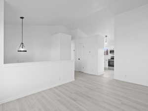 Spare room featuring light wood finished floors and lofted ceiling