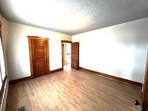 Bedroom #1 with wood finished floors and a textured ceiling