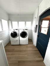 Laundry room featuring brick wall, light wood-style floors, washer and dryer, with both gas and electric connection.