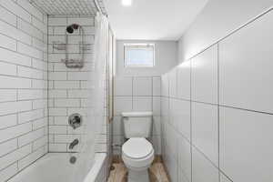 MIL - Bathroom featuring shower / bath combo and tile walls