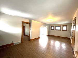 Upstairs living room with arched walkways and light wood-style flooring.  Amazing lighting, windows on every wall!