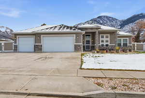Prairie-style house featuring a mountain view, stone siding, concrete driveway, and a garage