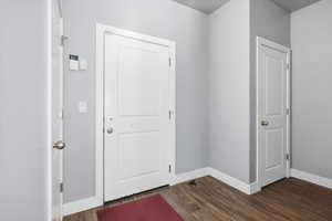 Hall featuring dark wood-type flooring and baseboards