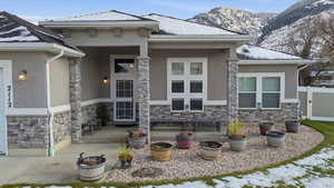 Entrance to property with stone siding, stucco siding, a porch, and a mountain view