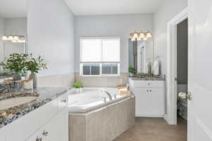 Primary bath featuring two vanities, a bath,  separate shower and light tile patterned flooring