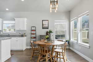 Dining area featuring dark wood-style floors and a chandelier