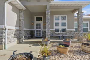 Property entrance featuring stone siding, stucco siding, and a patio area