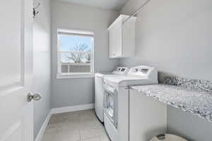 Laundry area with light tile patterned floors, cabinet space, and washer and dryer