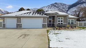 Most home featuring a garage, driveway, stone siding, and a mountain view
