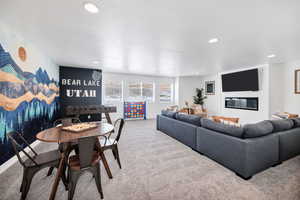 Carpeted living area with an accent wall, a textured ceiling, recessed lighting, and a large fireplace