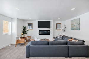 Carpeted living area with a textured ceiling, a fireplace, and recessed lighting