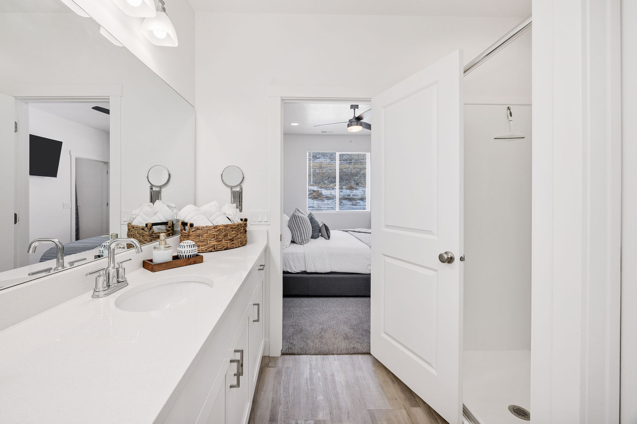 Ensuite bathroom featuring vanity, shower, light wood-style floors, and a ceiling fan