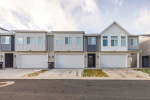 View of front facade with board and batten siding, concrete driveway, stone siding, and a garage