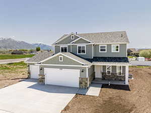 Craftsman house featuring covered porch, a shingled roof, stone siding, and driveway