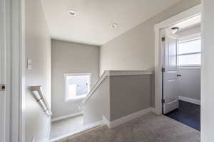 Hall with carpet floors, an upstairs landing, and recessed lighting