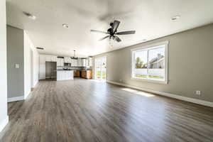 Unfurnished living room with dark wood-type flooring, a textured ceiling, a ceiling fan, and recessed lighting