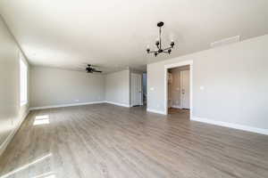 Spare room featuring a chandelier, a ceiling fan, and light wood finished floors