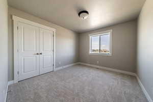 Unfurnished bedroom with a closet, light carpet, and a textured ceiling