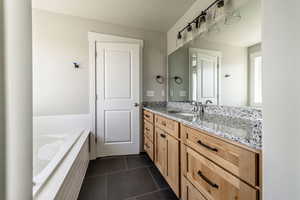 Full bath with vanity, dark tile patterned flooring, and a bathtub